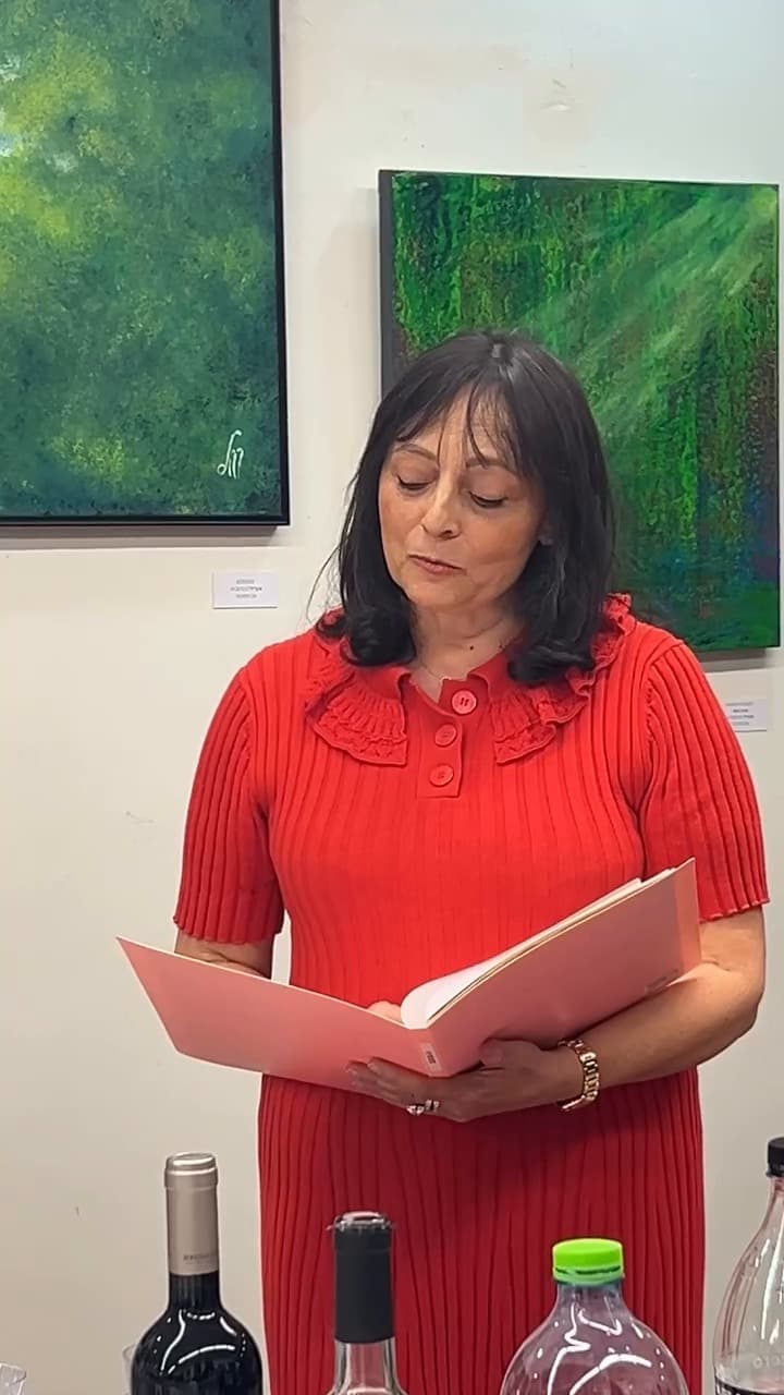 Woman in a red dress reading a text in front of two green paintings at the Échappées belles exhibition