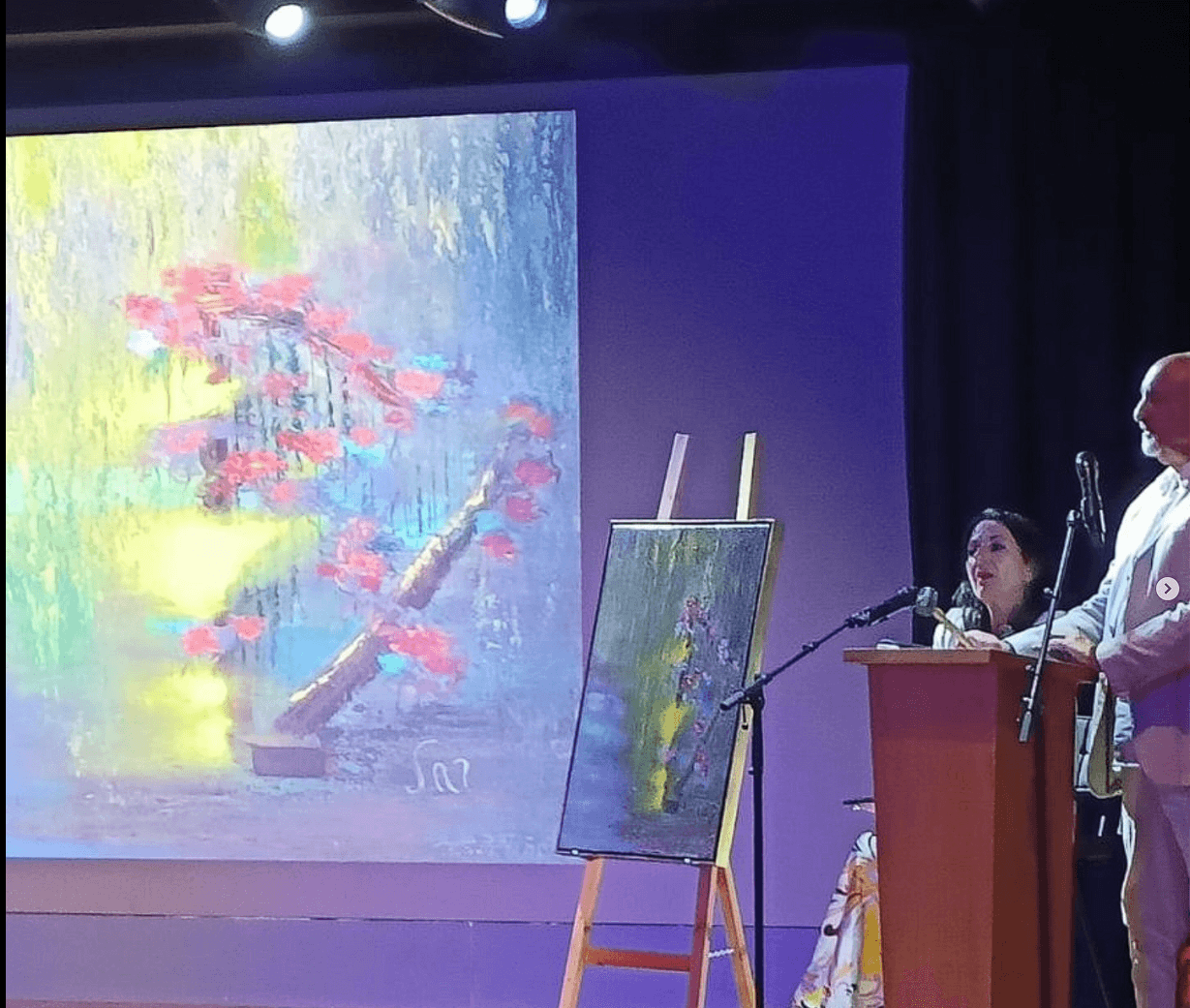 Martine Rachel Ovadia on stage at the Museum of Hebrew Music, next to one of her paintings